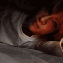 a close up of a person laying on a bed with a cup of coffee