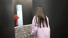 a woman in a purple jacket is walking down a hallway