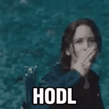 a woman is holding a gold coin with a poop on it and says hodl .