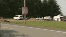 a no smoking sign is on a pole in the middle of the road
