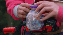 a person in a pink jacket is holding a toy that looks like a robot