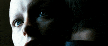 a close up of a person 's face in the dark with blue eyes