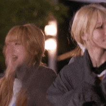 two blonde women are standing next to each other and one is smiling
