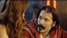 a man with a mustache looks at a woman