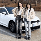 two women standing in front of a white kia