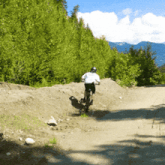 a person riding a bike on a dirt road with mountains in the background