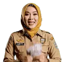 a woman wearing a hijab and a tan uniform has the name sumantrien on her badge