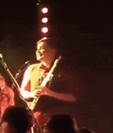 a man playing a guitar in front of a crowd