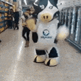 a cow mascot is standing in a store .