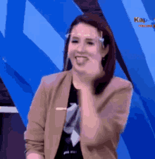 a woman wearing a face shield is laughing and sticking her tongue out while standing in front of a blue wall .