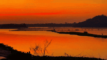 a sunset over a body of water with a small island in the middle