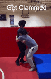 two people are wrestling in a gym with the words get clammed above them