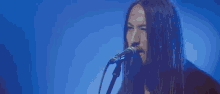 a man playing a guitar and singing into a microphone on stage