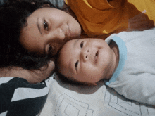a woman laying on a bed next to a baby