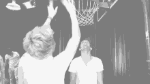 a man throws a basketball into a basketball hoop in a black and white photo