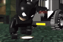 a lego batman is standing next to a plate