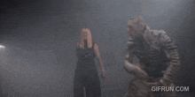 a man and a woman are standing in a dark room with a gifrun.com logo in the corner .