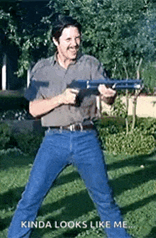 a man is holding a gun in his hand and smiling while standing in the grass .