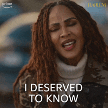 a woman says " i deserved to know " in front of a harlem poster