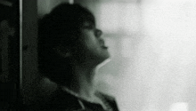 a black and white photo of a man leaning against a wall with his head down .