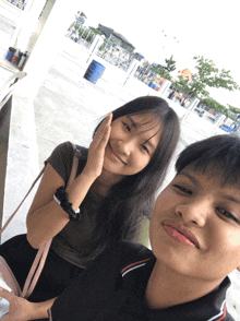 a boy and a girl are posing for a picture and the girl is touching her face