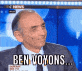 a man in a suit and tie is sitting in front of a screen that says ben voyons ..