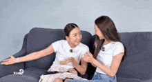 two women are sitting on a couch and one of them is wearing a t-shirt that says ' yaoi '