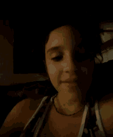 a close up of a woman 's face in the dark with a necklace around her neck .