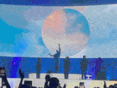 a group of people standing on a stage in front of a large sphere
