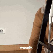 a person standing in front of a wall with the word mcdh written on it