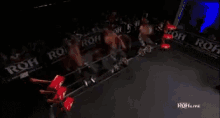 a group of men are wrestling in a ring with a sign that says roh live in the background