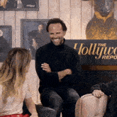 a man is sitting in front of a sign that says the hollyw