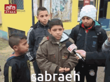 a group of young boys are being interviewed by a man with a microphone and the word sabraeh on the bottom