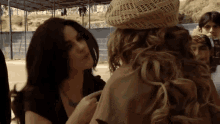 two women are standing next to each other and one has a hat on