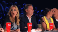 a group of people are sitting at a table with dunkin donuts cups .