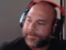 a bald man with a beard wearing headphones with his eyes closed .