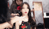 a woman with a red rose in her hair is getting her hair styled