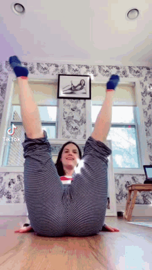 a woman is doing a yoga pose with her legs up in the air .