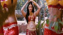 a woman in a red and gold costume is dancing in a forest .