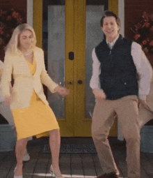 a man and a woman are dancing on a porch in front of a yellow door .