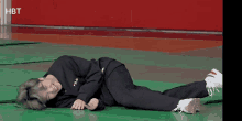 a person wearing a fila sweatshirt is laying on their stomach on a green mat