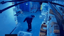 a man in a black hoodie is standing in a warehouse surrounded by boxes