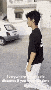 a man wearing a black shirt with the number 8 on it is walking in front of a white car