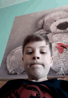 a young boy making a funny face in front of a picture of a teddy bear