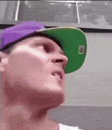 a man wearing a green hat and a purple hat is making a funny face .