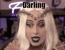 a woman wearing a wig and a crown with the word darling on her head .
