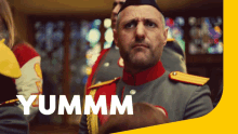 a man in a military uniform is standing in front of a yellow border that says yummm
