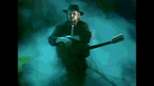 a man in a cowboy hat is holding a guitar