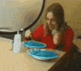a woman is sitting at a table eating a plate of blue spaghetti .