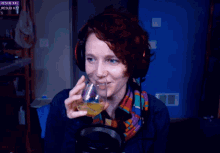 a woman wearing headphones and a scarf holds a glass in front of a screen that says resub x42